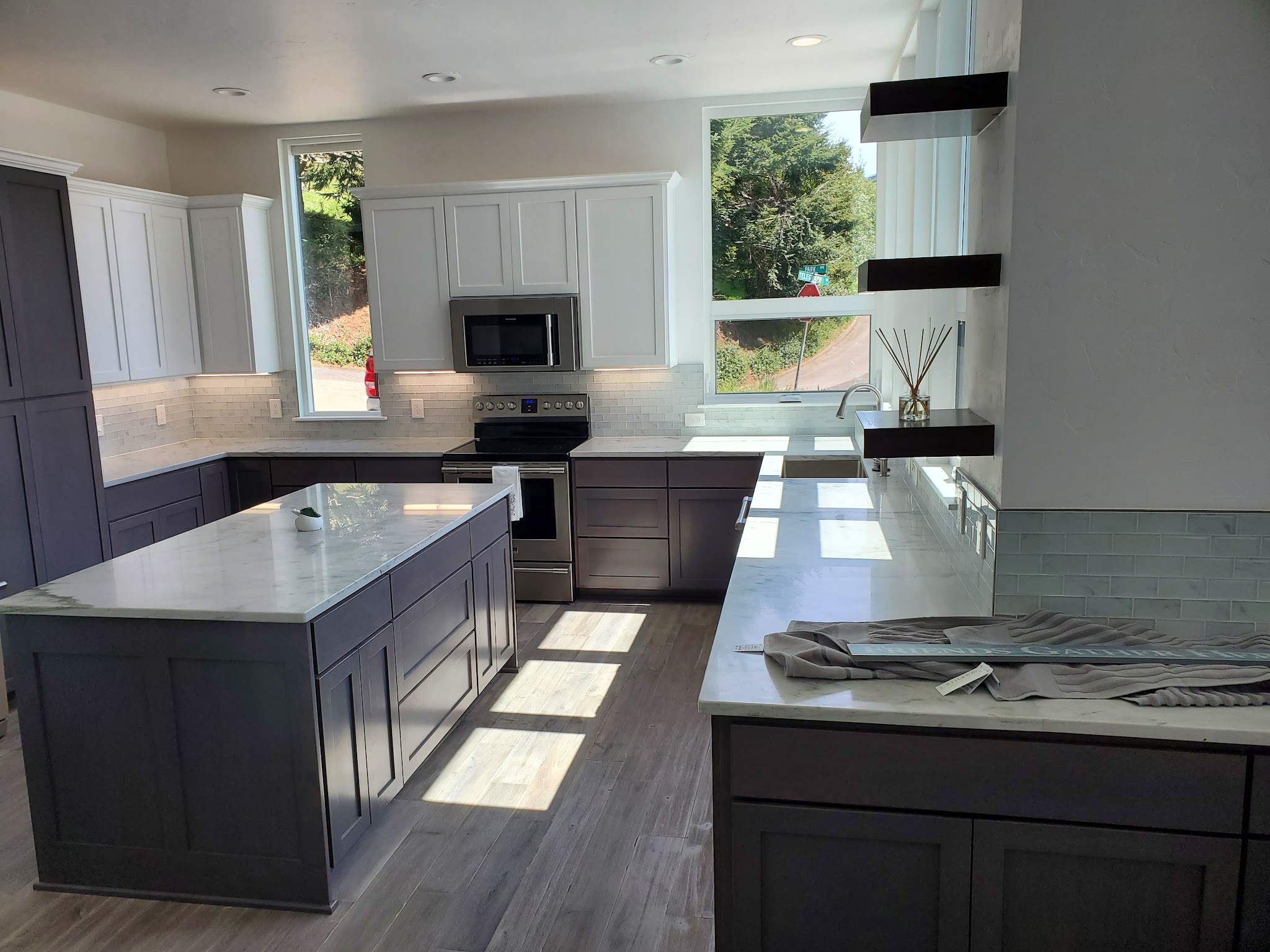 A finished kitchen remodel with gray island cabinets, white uppers and quartz countertops