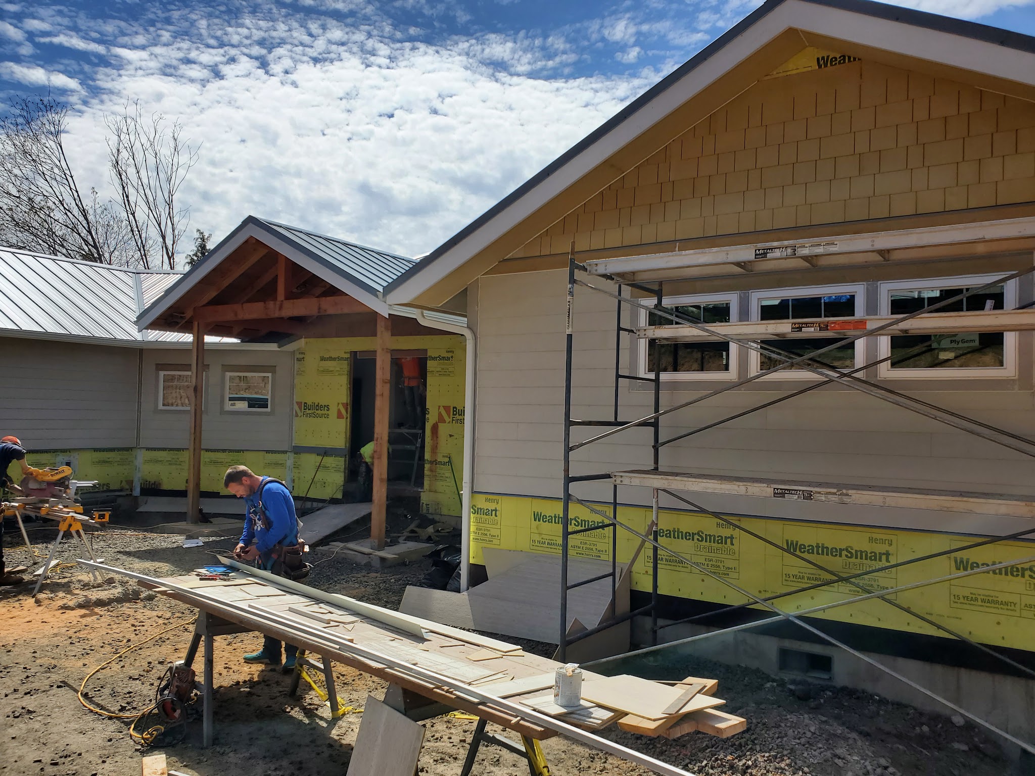Crew installing weather-resistive barrier and trim on a new build