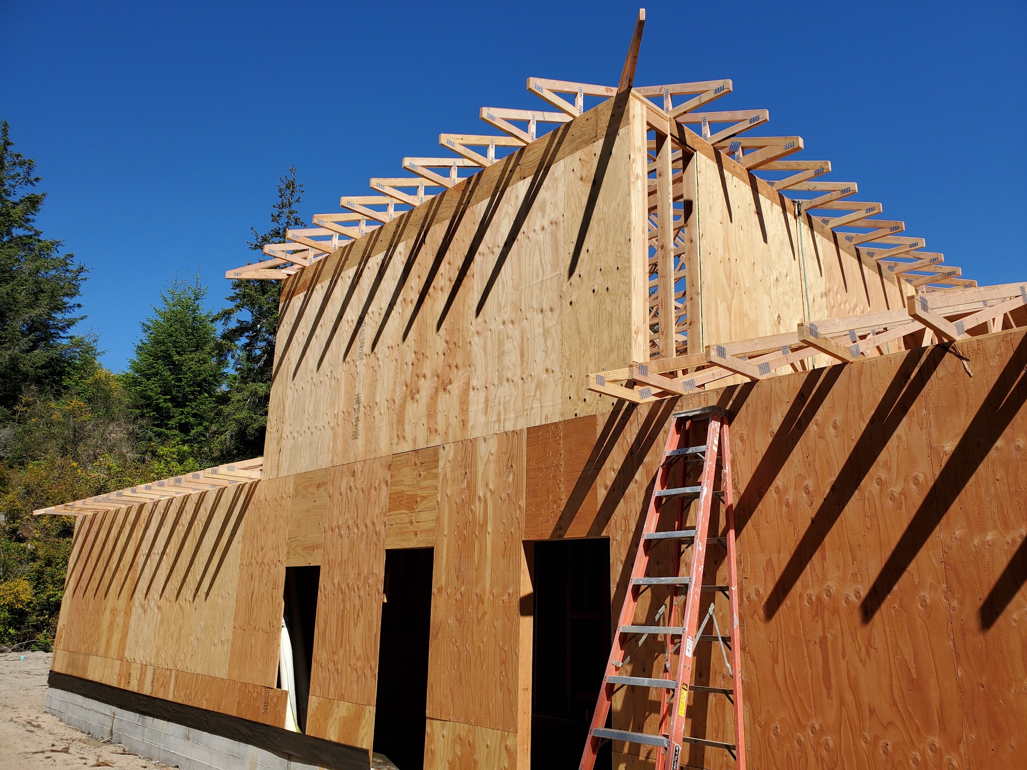 Roof truss framing under construction against a blue sky
