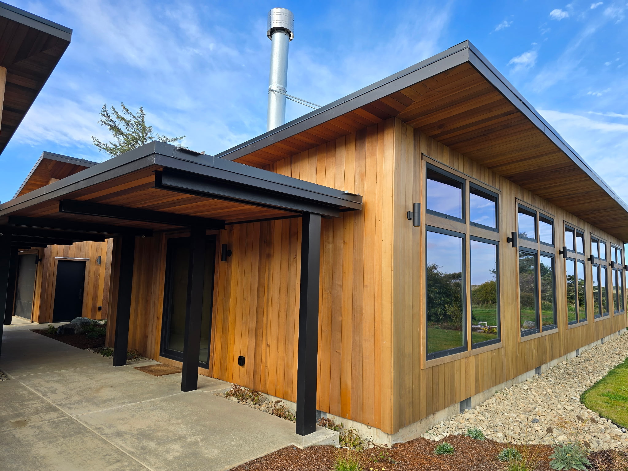 A finished cedar home exterior with a covered walkway and black steel accents